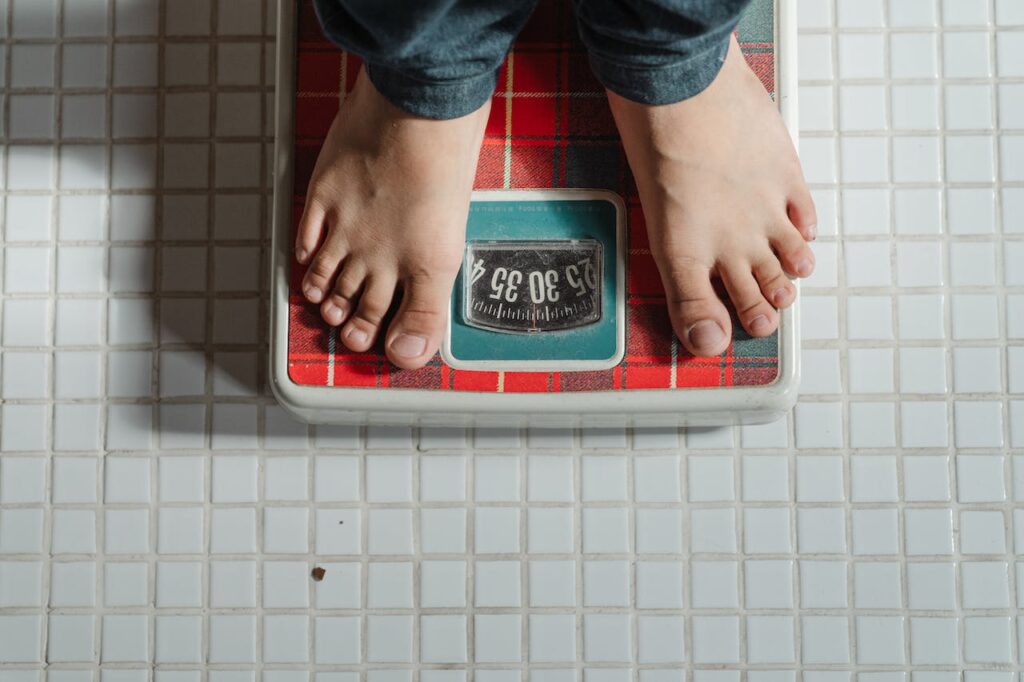 Close-up image of a scale displaying weight, with legs resting on it, emphasizing the concept of choosing low glycemic foods for better health.